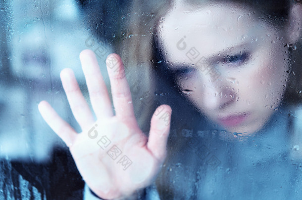忧郁和悲伤的女孩在雨中的窗口