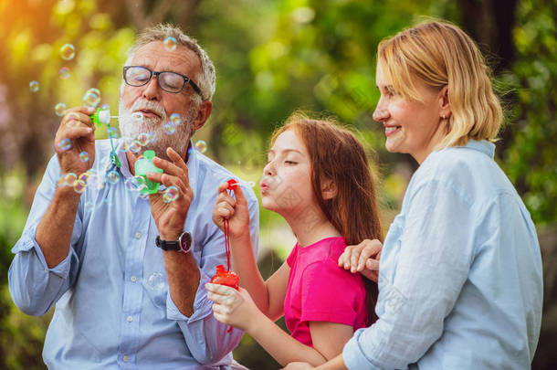 快乐的家庭在夏天周末去花园公园度假时一起吹肥皂泡。儿童教育和家庭活动概念.