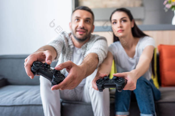 选择焦点的已婚夫妇与游戏板玩视频游戏一起坐在沙发上在家