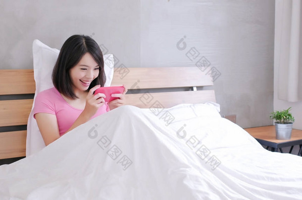 在床上愉快地玩手机游戏的妇女