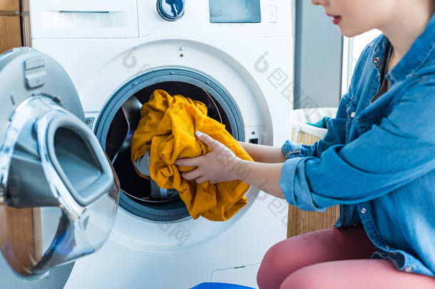 女青年把洗<strong>衣服</strong>放进洗衣机的镜头