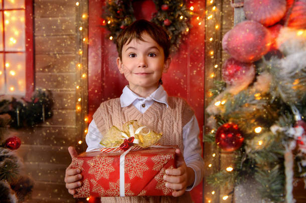 漂亮男孩站在装饰着圣诞礼物盒的房子的门廊上。奇迹的时刻. 