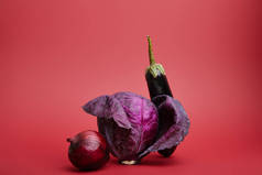 在红色背景上的新鲜成熟有机洋葱, 卷心菜和茄子的特写镜头视图 