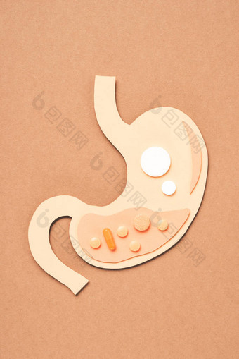 在米色的不同药片的人胃的顶部视图图片