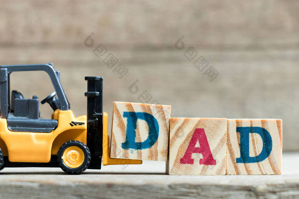玩具黄色叉车持有字母块 D 完成字爸爸在木头背景 (父亲天的概念)