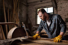 木工在锯木厂用机器锯的防护手套和谷歌