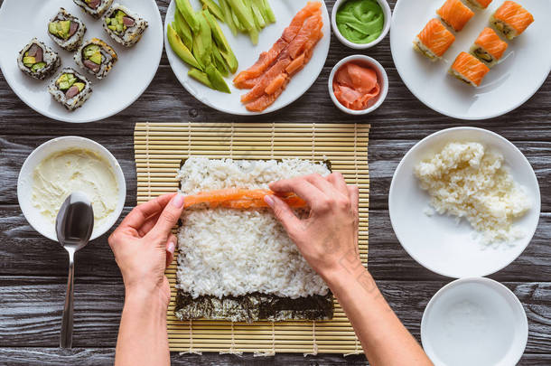 人的部分上部看法烹调美味寿司卷与鲑鱼, 米和紫菜  