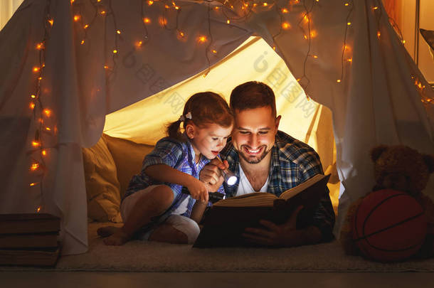 快乐家庭的父亲与子女女儿在帐篷里看书 