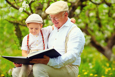 祖父与孙子读书在春天的花园