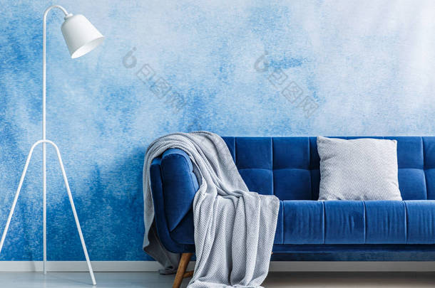 海军蓝色沙发与毯子和枕头, 灯设置在贝尔奥伯尔墙壁在客厅内部