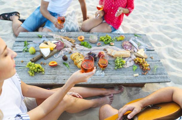 夏季海滩野餐喝玫瑰酒的年轻朋友