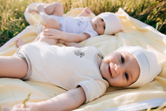 有趣的双胞胎姐妹新生婴儿躺在草地上，在夏季的一天