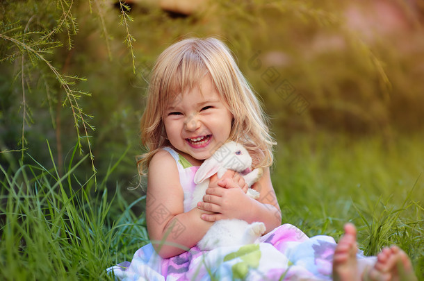 可爱的小女孩与小兔子有一个复活节在绿草