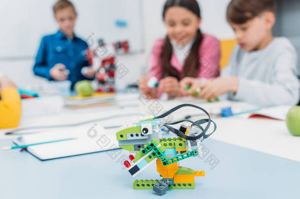 五颜六色的手工机器人在办公桌与学童在茎类的背景