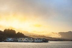 金色的夕阳，越过高山，湾和沿海房屋