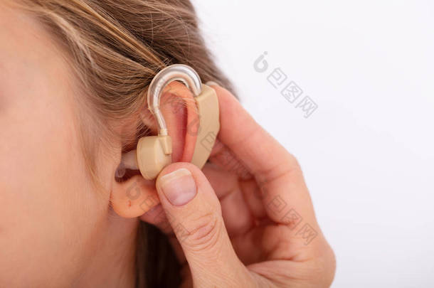 特写镜头的医生手插入助听器在女孩的耳朵