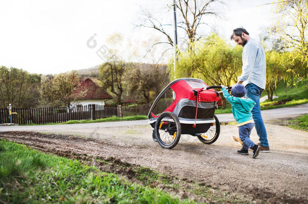一个孩子的父亲在春天的时候把一辆慢跑的婴儿车推到外面.
