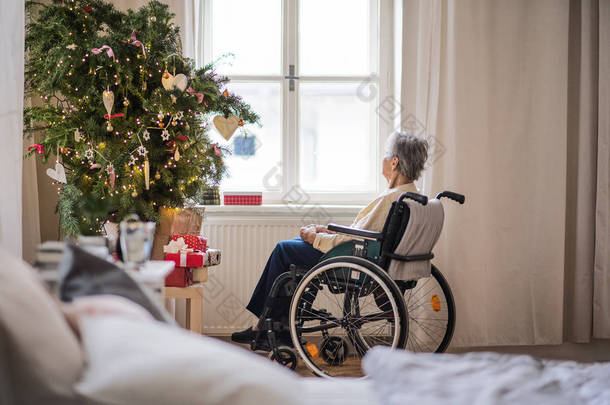 <strong>圣诞节</strong>期间在家中坐轮椅的一名高级妇女的后视镜.