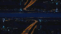 空中夜景的河桥与移动的汽车和城市与夜灯, 镜子地平线的效果。媒体。令人惊叹的夜景城市和跨江大桥, 开始主题.