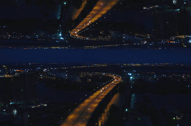 空中夜景的河桥与移动的汽车和城市与夜灯, 镜子地平线的效果。媒体。令人惊叹的夜景城市和跨江大桥, 开始主题.