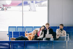在机场候机楼等候航班的年轻朋友手持文件和使用笔记本电脑