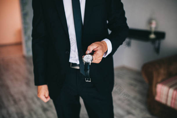 早在婚礼前新郎或时尚男子商人把手表放在他的手