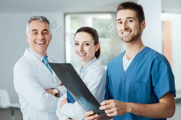 Medical team posing and <strong>ex</strong>amining an x-ray image