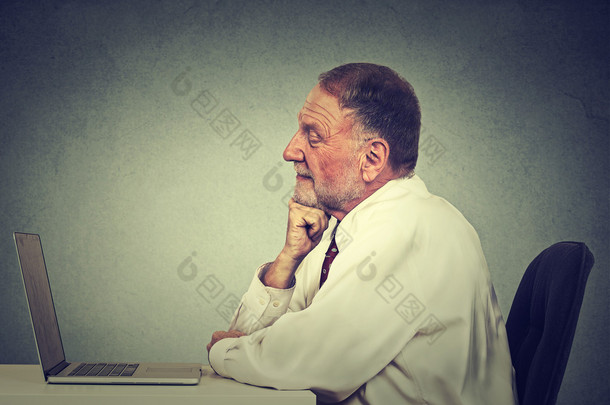 老人使用手提电脑阅读电子邮件消息。电子学习概念 
