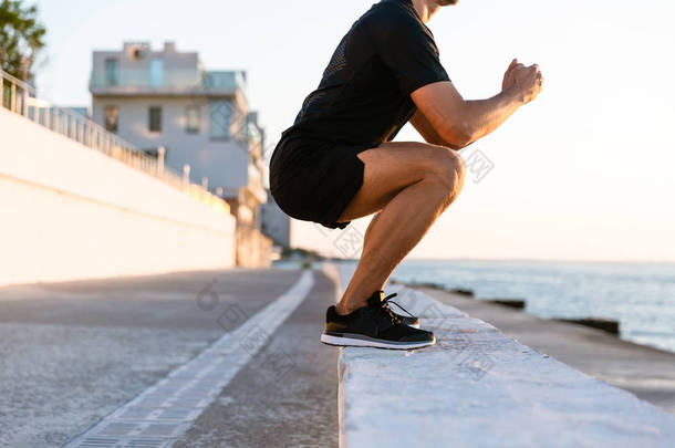 在海边的栏杆上的运动员站立蹲下的裁剪镜头