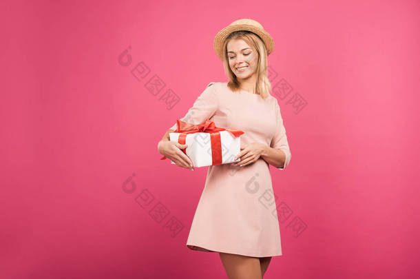 快乐的女人在草帽举行目前孤立在粉红色 