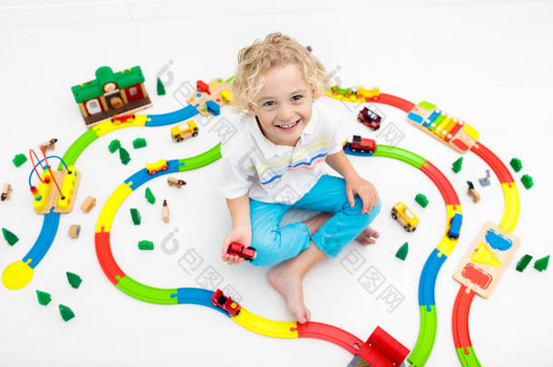 孩子们玩玩具火车铁路.孩子们在玩彩色彩虹木火车.给<strong>小</strong>男孩的玩具学龄前儿童在家里或托儿所、幼儿园建造铁路。幼儿园教育游戏.