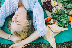 夏日野餐放松的年轻女子躺在垫子上, 健康的食物 