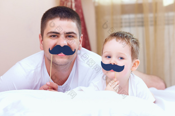 有趣的父亲和儿子一起假胡须，在家里玩，