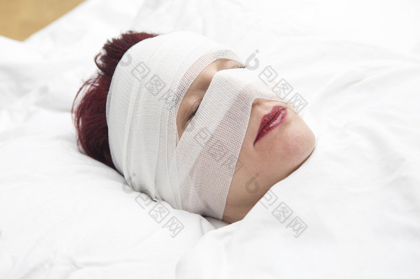 女人在床上用绷带缠在她的头的特写
