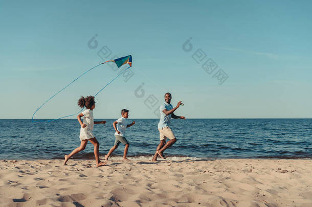 父亲和孩子们在海滩上玩风筝