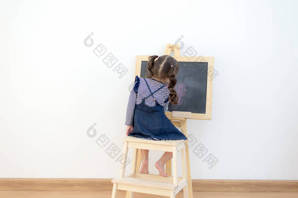 可爱的小女孩在家里画<strong>黑板</strong>。生活方式概念