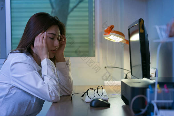 年轻疲乏的商业妇女头疼坐在<strong>计算机</strong>在得