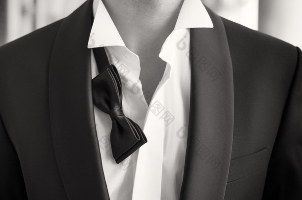 Close-up photo of man in tuxedo with <strong>open</strong> shirt and loose bow tie