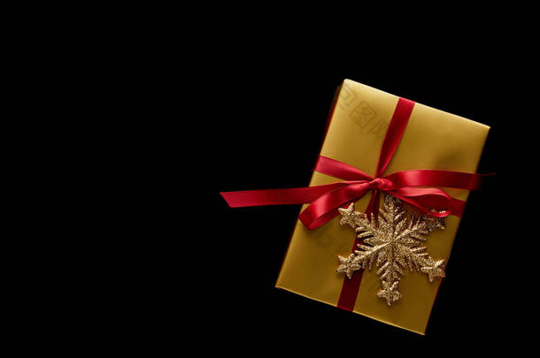 闪烁着金色圣诞礼物的顶视图，红色的缎带和被黑色隔离的雪花