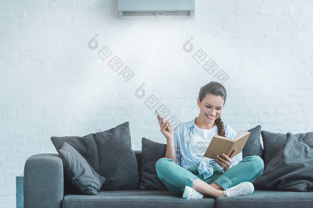在家中使用<strong>遥控</strong>器打开空调的快乐女人看书