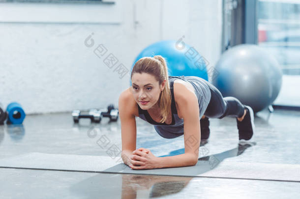 运动的年轻女子做板练习瑜伽垫