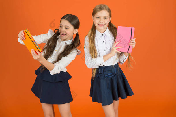 亲爱的日记学校文具。女孩可爱的孩子校服橙色<strong>背景</strong>。女学生展示书籍日记或记事本。学校用品概念。我们喜欢在学校<strong>学习</strong>。朋友记事本的个<strong>人</strong>资料