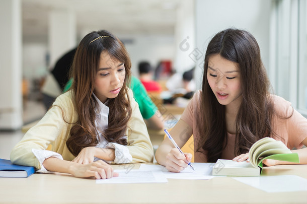 亚洲学生在图书馆工作.