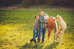 幸福的家庭乐趣与马在户外在绿色的田野上夏季的一天
