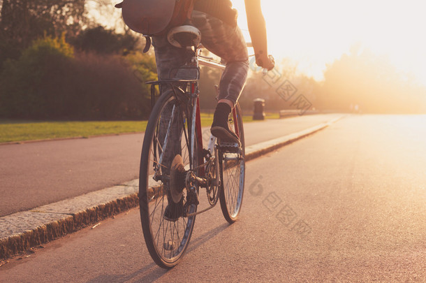 在日落时在公园里骑自行车的年轻女子