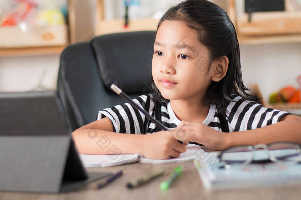 亚洲小女孩做家庭作业和手指在木桌上选择焦点浅景深