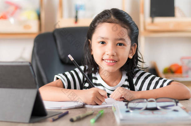 亚洲小女孩做家庭作业和手指在木桌上选择焦点浅景深