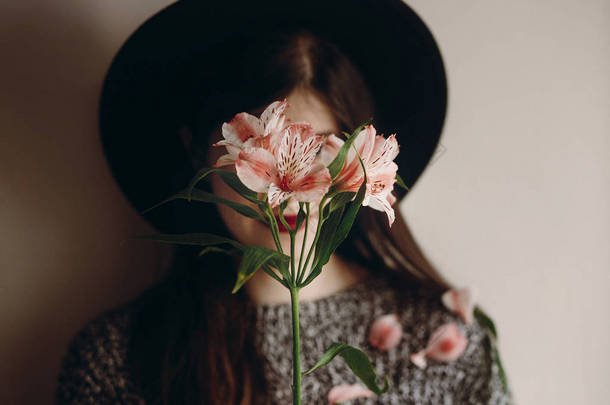 时尚的波西米亚女人手里拿着美丽的 alstroemeria 花。把注意力放在花上。生态概念。保存和保护