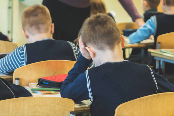 在学校上课累了的小学生。后退视图.