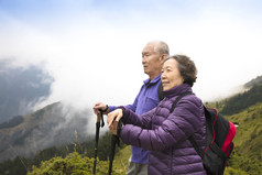 幸福的亚洲高级夫妇在山上徒步旅行